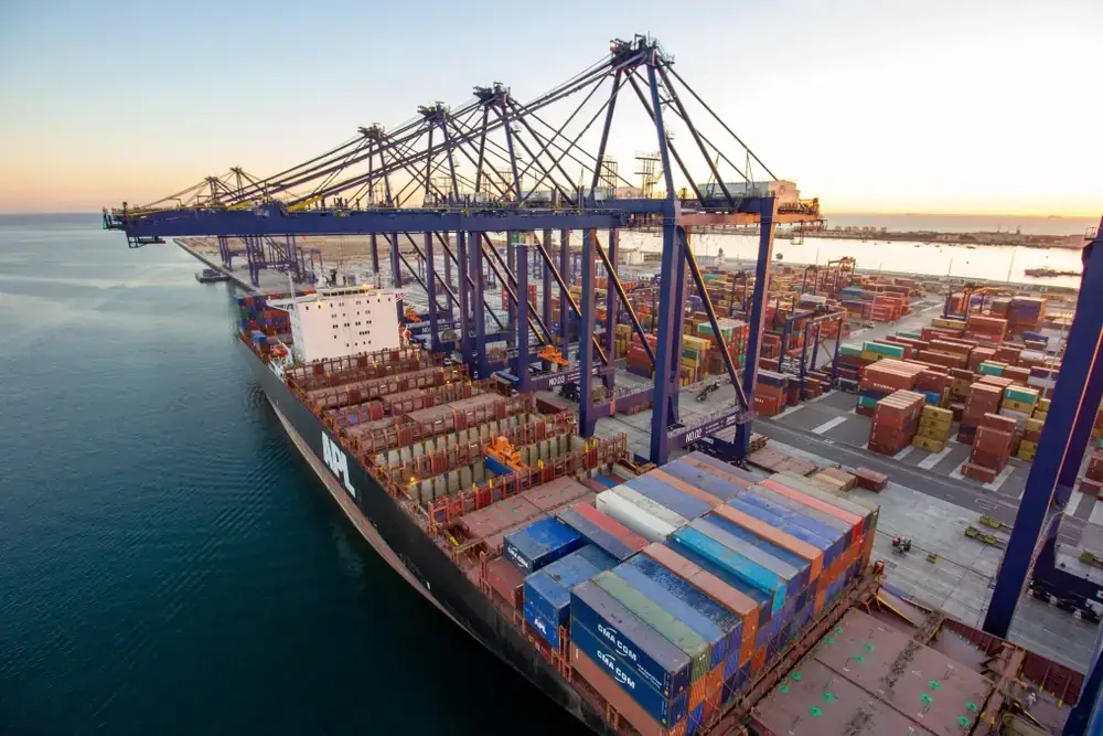 Container ship being loaded under cranes at sunset