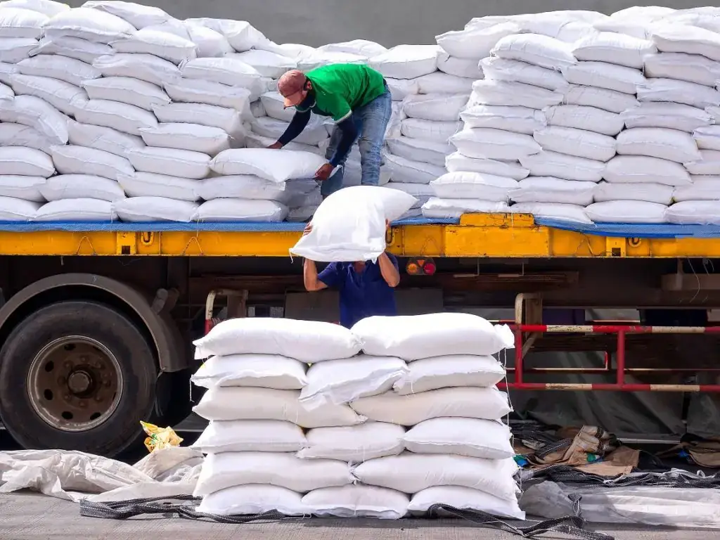 Workers loading white sacks onto a truck